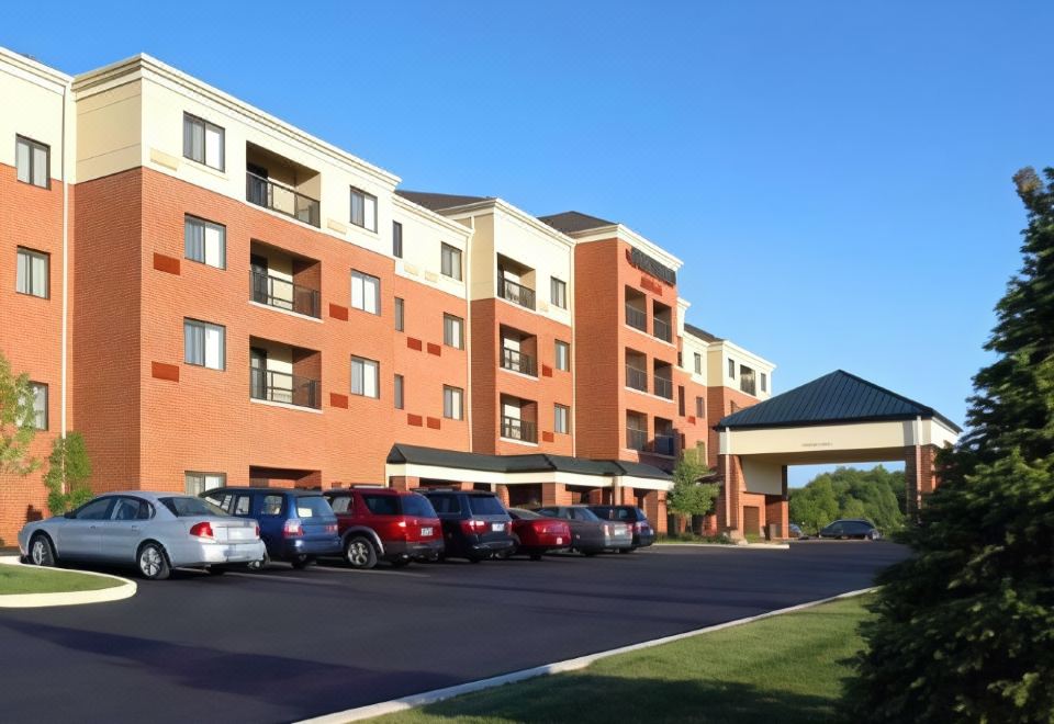 a row of cars is parked in front of a large , modern apartment building with a red - brick exterior at Courtyard Akron Stow