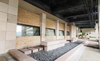 There is an outdoor seating area along a wall adorned with numerous stones at Winland 800 Hotel