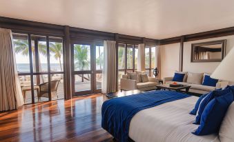 a spacious bedroom with hardwood floors , a large bed , and a view of the ocean at Sinalei Reef Resort & Spa