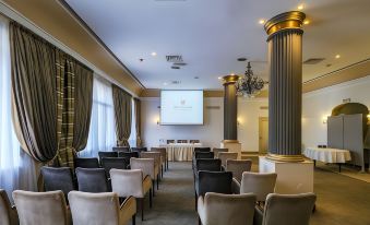 a conference room with rows of chairs arranged in a semicircle , and a large screen mounted on the wall at Majestic Hotel