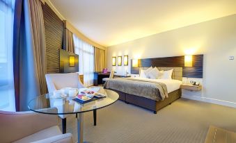 a modern hotel room with a bed , nightstands , and a dining table , all neatly arranged at Cork International Hotel