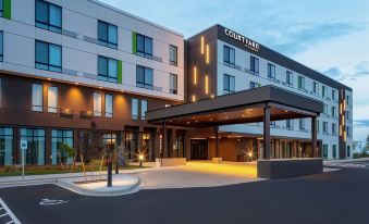 "a large , modern hotel building with the name "" courtyard by marriott "" on it , surrounded by trees and parking lot" at Courtyard Pasco Tri-Cities Airport