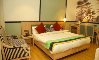 a modern bedroom with a wooden bed , green striped blanket , and red pillows , along with a nightstand and chair at Amara Hotel