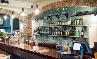 a well - stocked bar with various bottles of alcohol , a large wooden counter , and various electronic devices at Porto Resort