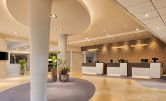a modern hotel lobby with a reception desk and a large vase of flowers at DoubleTree by Hilton Manchester Airport