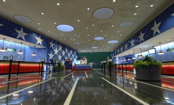 a large room with a red and blue star patterned wall , a glass ceiling , and several people walking around at Disney's All-Star Sports Resort