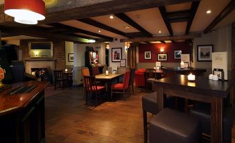 a dimly lit restaurant with wooden tables and chairs , red booths , and framed pictures on the walls at Swindon North