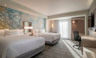 a hotel room with two white beds , a blue and gray accent wall , and a black chair at Courtyard Ciudad Juarez