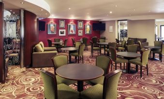 a well - appointed hotel lobby with multiple chairs and tables arranged for guests to sit and relax at Caledonian Hotel