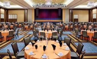 a large , well - lit conference room with multiple tables set up for a formal event , including chairs , place settings , and televisions at Blue Chip Casino Hotel and Spa