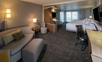 a modern hotel room with a large bed , couch , and desk , as well as a desk area and a kitchenette at Courtyard Bay City