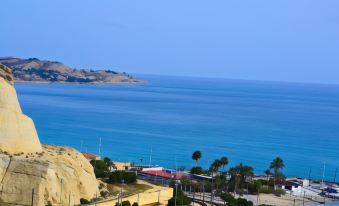 a scenic view of a coastline with a highway running along the shore and buildings in the distance at Hotel Maya Alicante