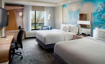 a modern hotel room with two beds , a window offering a view of the city , and a desk at Courtyard LaGrange
