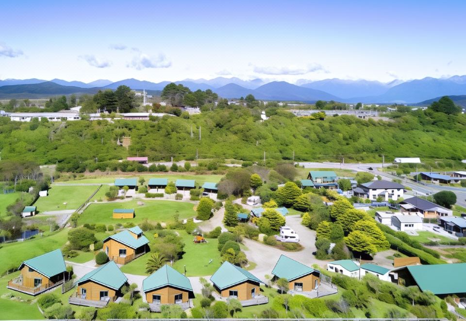 an aerial view of a residential area with multiple houses , surrounded by green trees and mountains in the background at Shining Star Beachfront Accommodation