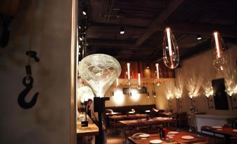 a restaurant with wooden tables and chairs , a large glass sculpture in the middle of the room , and hanging light fixtures at Hotel Milano
