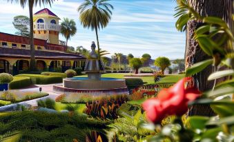a lush green garden with a fountain in the middle , surrounded by various plants and flowers at Mission Inn Resort & Club