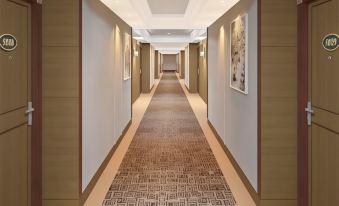 a long hallway with a brown carpet and white walls , featuring several paintings on the left side at Classic Hotel Muar