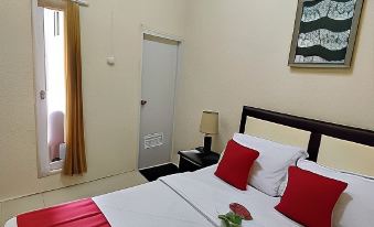 a clean and well - organized hotel room with a large bed , two nightstands , and a door at Bakom Inn Syariah