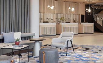 a modern hotel lobby with a white couch , chairs , and a small round table in the middle at Courtyard Basel