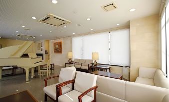 a modern office space with white furniture , including sofas and armchairs , arranged around a central console table at Hamamatsu Hotel