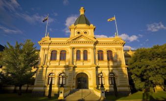 a large , ornate building with a dome and flagpoles in front of it , under a blue sky at Hotel Grand Chancellor Launceston