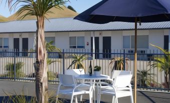 a table and chairs are set up under an umbrella in front of a building at Motel Oasis