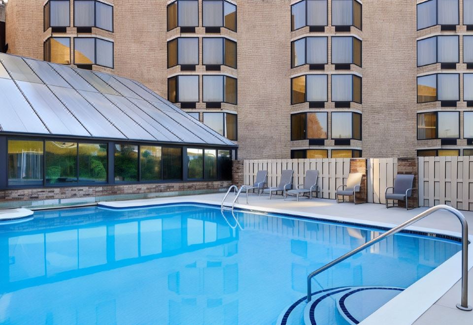 a large swimming pool with a curved edge is surrounded by lounge chairs and buildings at DoubleTree by Hilton Hotel Oak Ridge-Knoxville