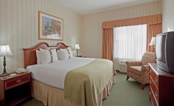 a large bed with a green blanket and white pillows is in a room with a window at Airport Inn Manchester