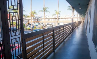a long , empty walkway with metal railings and a view of palm trees and cars in the background at The Dixie Hollywood