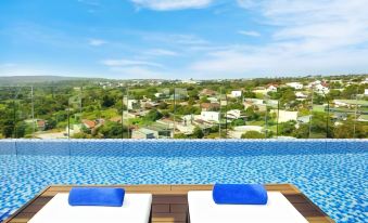 a large swimming pool with blue water and white lounge chairs overlooks a city view at Boston Hotel