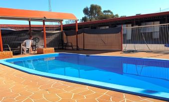 a large blue swimming pool surrounded by a brick patio , with a gazebo and lounge chairs nearby at Ardeanal Motel