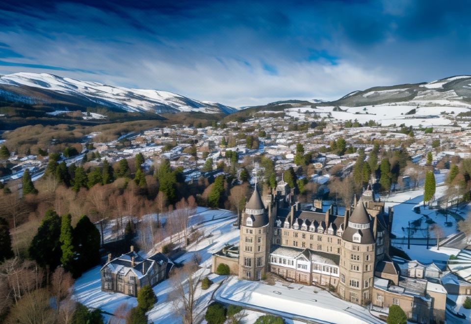 aerial view of a snow - covered town with a castle in the middle , surrounded by snow - covered mountains at The Atholl Palace