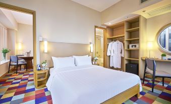 The bedroom features a spacious bed and desk, with an open closet door beside them at Hotel COZI Harbour View