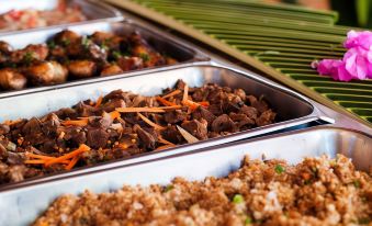 a variety of dishes are displayed in metal trays , including a brown dish with carrots at Beachcomber Island Resort