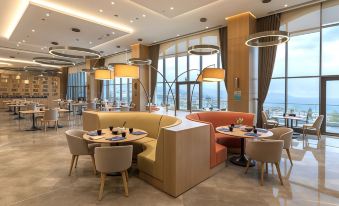 a modern dining area with multiple tables and chairs , featuring a large window overlooking the ocean at Radisson Blu Hotel Trabzon