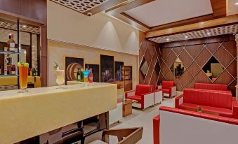 a modern restaurant with red chairs and white tables , surrounded by artwork on the walls at The Fern Residency Aurangabad