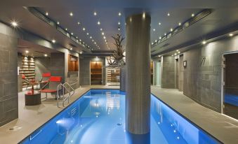 an indoor swimming pool with a blue light , surrounded by white walls and gray ceiling at Avenue Lodge Hotel & Spa