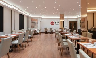 a large dining room with wooden floors , white tables and chairs , and a red logo on the wall at Exe Salamanca