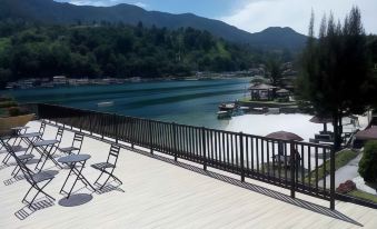 a wooden deck overlooking a body of water , with a lake in the background and several boats docked nearby at Khas Parapat