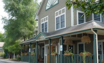 "a large building with a porch and a sign that says "" hemingways "" is surrounded by trees" at The Craftsman Inn & Suites