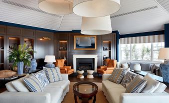 a modern living room with two white couches , orange chairs , and a fireplace under white pendant lights at Anchorage Port Stephens