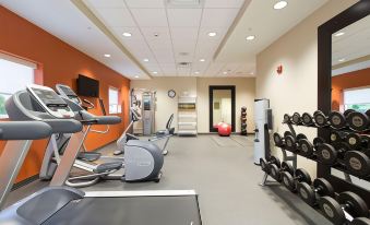 a well - equipped gym with various exercise equipment , including treadmills , stationary bikes , and weights , as well as a window at Home2 Suites by Hilton Canton