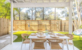 a patio with a dining table set for four people , surrounded by a wooden fence at Hastings Cove Holiday Apartments
