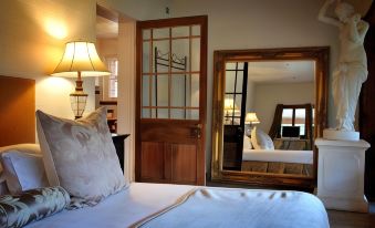 a bedroom with a bed , lamps , and a mirror on the wall , reflecting the room 's interior at Jacobs Creek Retreat