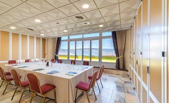 a conference room with a large window , red chairs , and a table set for a meeting at Sercotel Hotel Bahia de Vigo