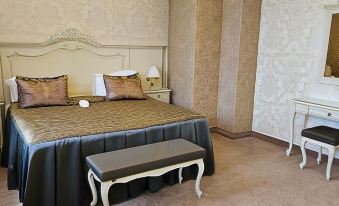 a bedroom with a large bed and a bench in front of the bed , creating a cozy and inviting atmosphere at Savoy Hotel