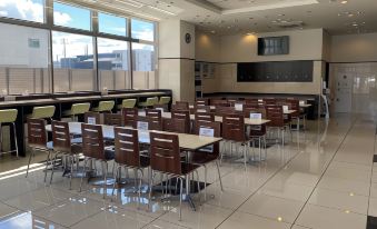 a large , empty classroom with wooden tables and chairs arranged in rows , possibly for a classroom setting at Toyoko Inn Meitetsu Chiryu Ekimae