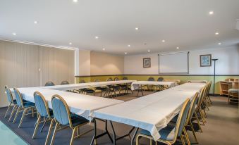 a large conference room with multiple rows of chairs arranged in a semicircle around a table at Aspley Carsel Motor Inn