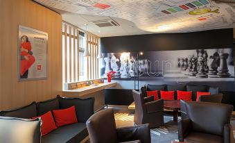 a modern lounge area with a black and brown color scheme , featuring comfortable seating arrangements and a large mural on the wall at Ibis Mulhouse Bale Aeroport