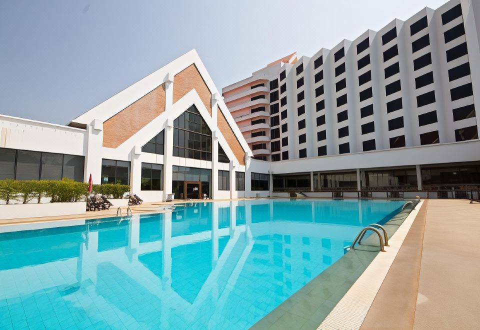 a large swimming pool is surrounded by a modern building and has a parking lot at Rimpao Hotel